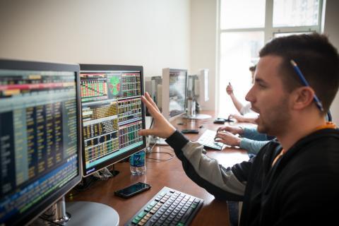 Student studying code and graphs on computer screens